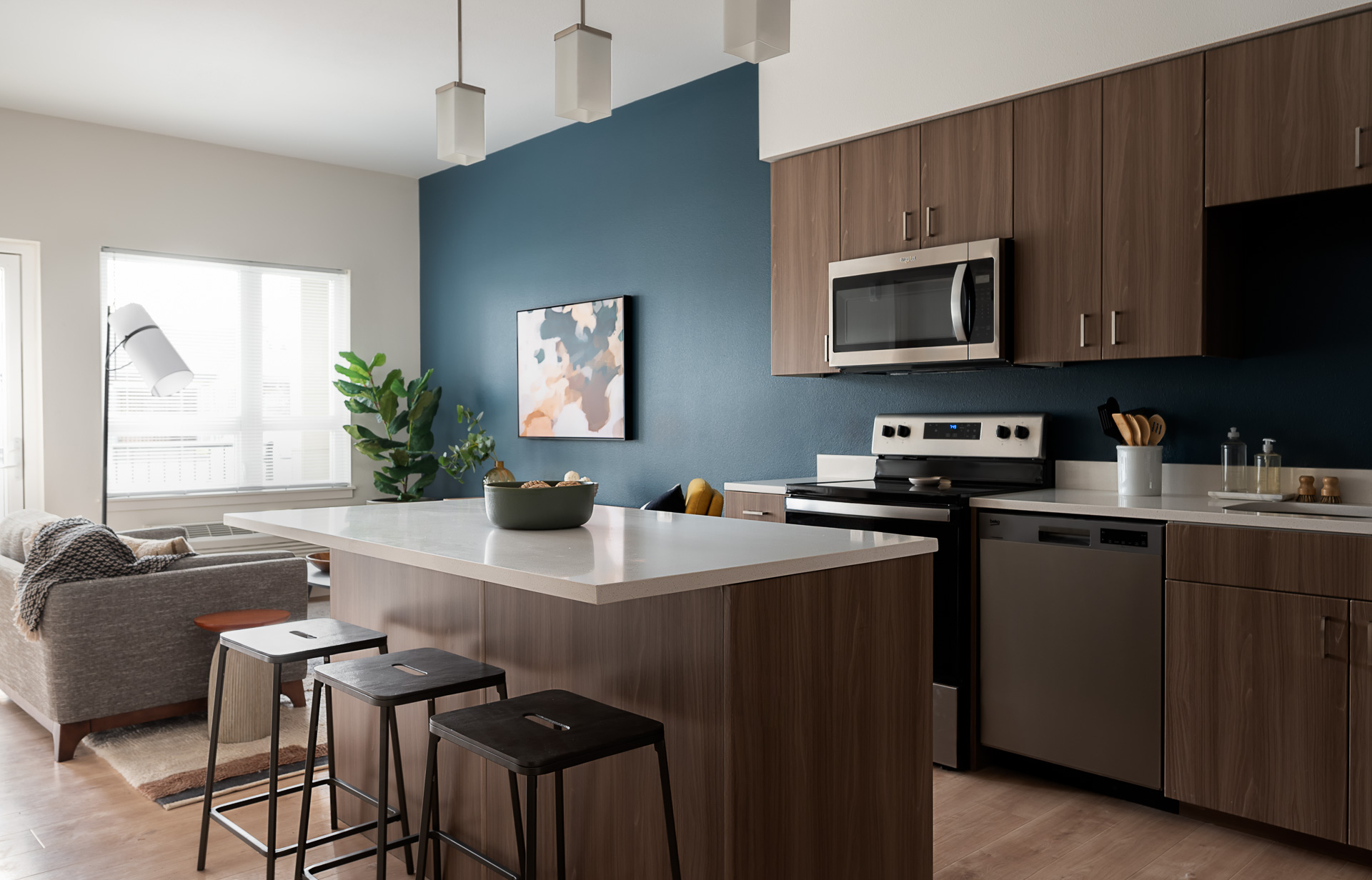 A modern kitchen with blue accent wall and walnut cabinets.