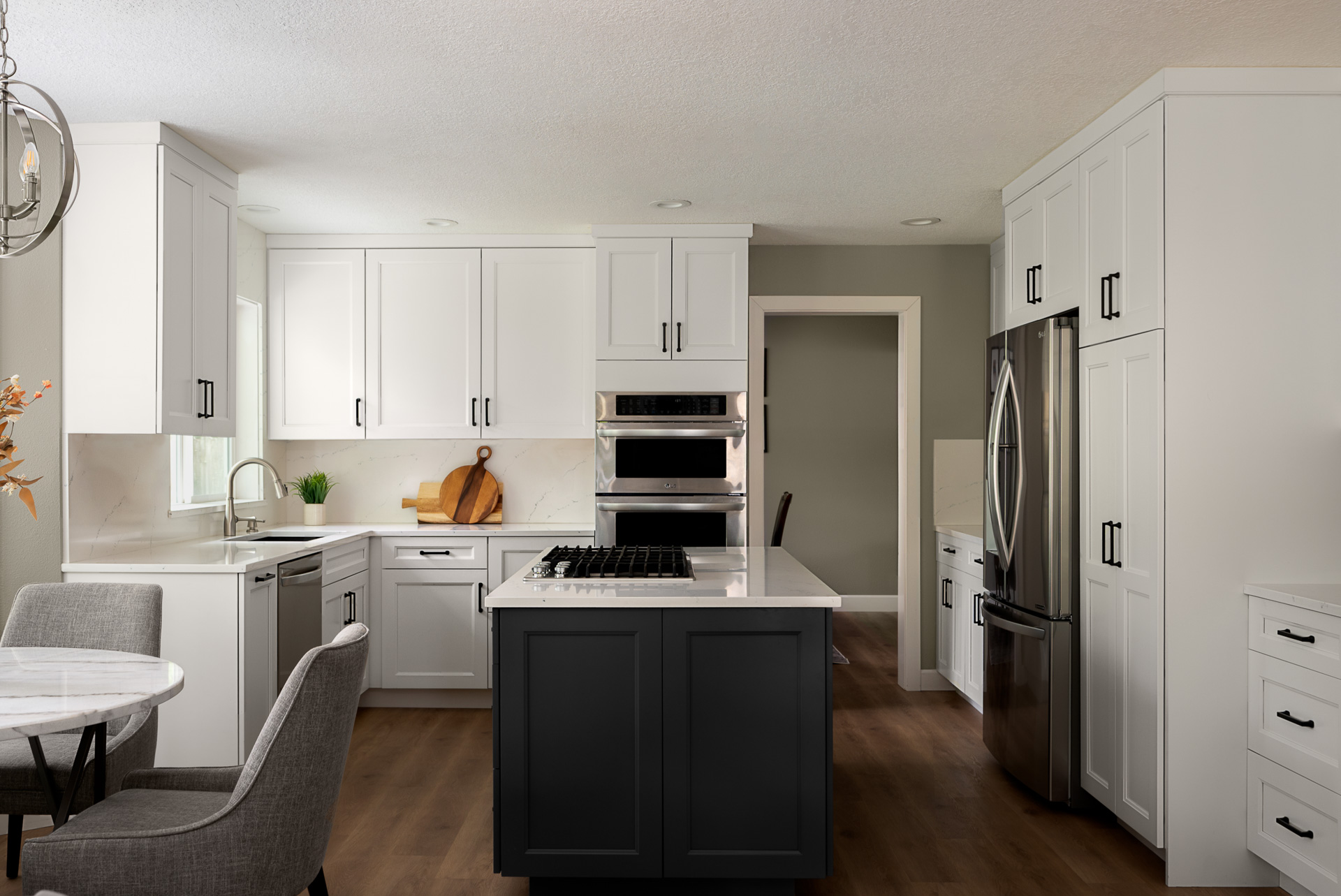 A modern white cabinet kitchen with dark island accent.